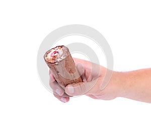 Hand holds roll of chocolate ice cream.