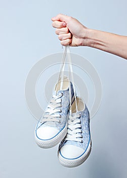 The hand holds by shoelaces retro style classic sneakers