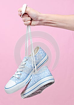 The hand holds by shoelaces retro style hipster sneakers