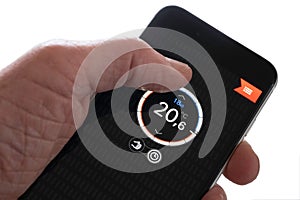Hand holds smartphone with thermostat app to control central heating temperature in house