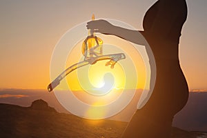 hand holds snorkeling goggles against the background of the sunset sky. Silhouette of a sexy woman holding scuba gear in