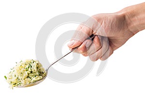 Hand holds a spoon on which the young boiled potatoes in dill