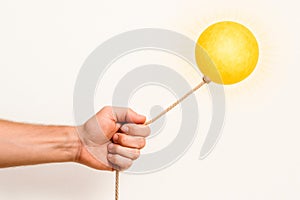 The hand holds the sun on the rope. Space for text.