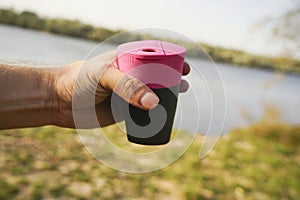 Hand holds tourist plastic glass on nature background