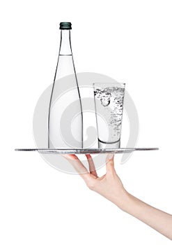 Hand holds tray with still water glass and bottle