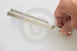 Hand holds Tuning fork for ear test of ENT doctor or sound wave maker on   white background with double exposure