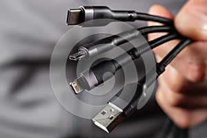 The hand holds a universal USB cable. USB Type C, Micro USB, Usb lightning