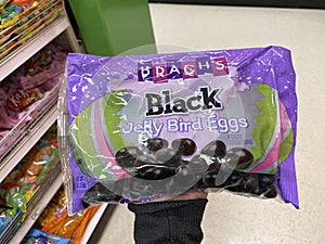 Eau Claire, Wisconsin - March 30, 2020: Hand holds up a package of Black Jelly Beans Brachs brand inside of the Easter Candy sec