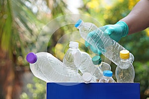 Hand holds used plastic bottle to put in junk bin for recycling. Concept, sorting garbage campaign before throw away