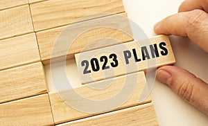 Hand holds a wooden cube with the text 2023 PLANS.
