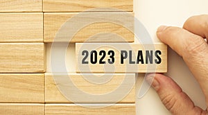 Hand holds a wooden cube with the text 2023 PLANS.