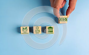 Hand holds wooden cubes with abbreviation ESG. ESG concept of environmental, social and governance. Sustainable corporation