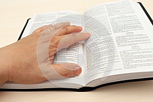 Hand on the Holy Bible in close-up. Studying and reading the Word of God. Top view