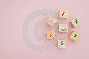 Hand and hospital symbol icon on wooden cube block among the multi color ribbons  for campaign world cancer day concept