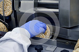 Hand of a human in glove works on conveyor. automatic line for the production of crispy whole grain bread at the factory