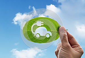 Hand of human is holding green leaf with EV Electric Vehicle, renewable energy carbon reduction