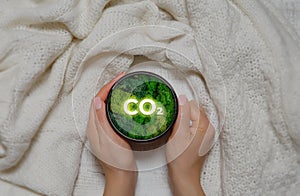 Hand of human holding mug with green plant and text as a symbol of protection of nature. Ecology and world sustainable environment