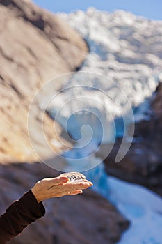 Hand with ice and Briksdal glacier - Norway