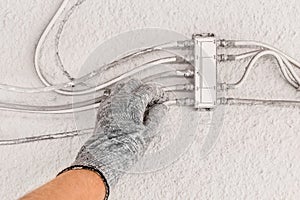 Hand of industrial worker in construction glove checks antenna splitter on white wall background