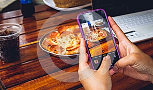 hand of person with mobile photographing food to publish on networks photo