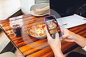 hand of person with mobile photographing food to publish on networks photo