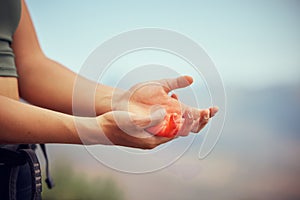 Hand injury, pain or accident of woman hiking outdoor on mountain for fitness and exercise. Closeup of injured or
