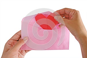 Hand inputting red heart paper origami into pink envelope