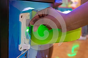 Hand insert a coin to children`s game console In the shoppingmall.