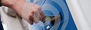 Hand inserting dollar money into bill acceptor closeup