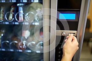 Hand inserting euro coin to vending machine slot photo