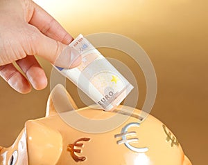 Hand inserting a fifty euro banknote into a piggy bank, concept for business and save money