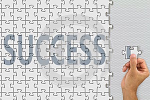 Hand inserting last missing piece jigsaw of word success