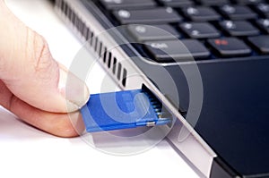 Hand inserting SD card in laptop