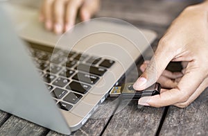 Hand inserting USB flash drive into computer laptop on the desk.