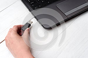 Hand inserting USB flash drive into laptop computer on white background. Close up of woman hand plugging pendrive on laptop.