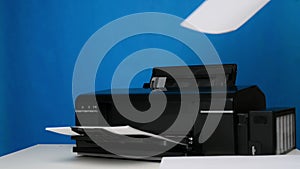 A hand inserts blank sheets of A4 paper into the printer on a blue background. Printing equipment