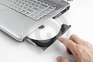 hand inserts dvd disc into laptop,