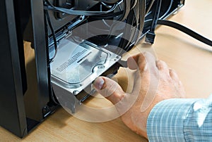 Hand inserts hard disk memory into system unit of computer