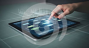 Hand interacting with digital tablet displaying a complex flowchart and data analytics interface