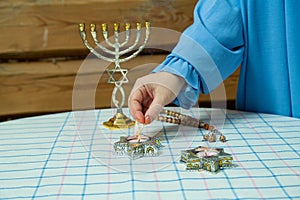 The hand of a Jewish woman lights candles in the Star of David candlesticks in honor of Shabbat