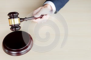 hand of Judge& x27;s holding wooden hammer knocking a gavel against w