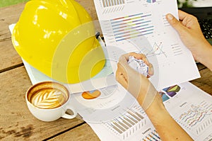 Hand keep crumpled paper with document chart and hot coffee cups on work table backgrounds