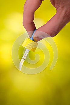 Hand keep a dropper on a natural background. Green background. Medicine, aromatherapy. Dropping pipette.