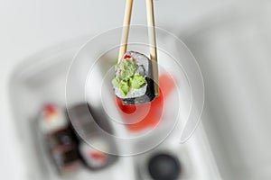 Hand keep roll with chopsticks, rolls, sushi. chopsticks, ginger, soy sauce in container delivery.