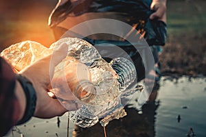 hand keeping plastic bottle and garbage in the nature