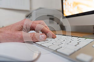 Hand on a keyboard with monitor and computermouse