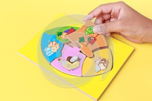 Hand of kid holding wooden jigsaw of the 5 food Groups. Child de photo