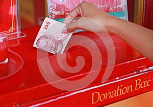 Hand of kid putting money for offertory in donation box photo