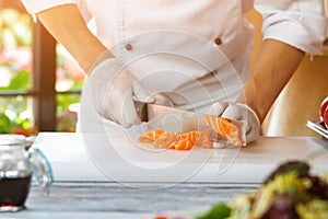 Hand with knife cutting fish.