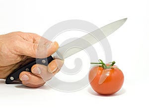 A hand with knife and tomato